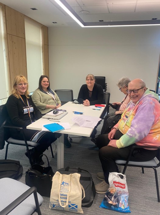 NETRALT members smiling, sitting round a table.