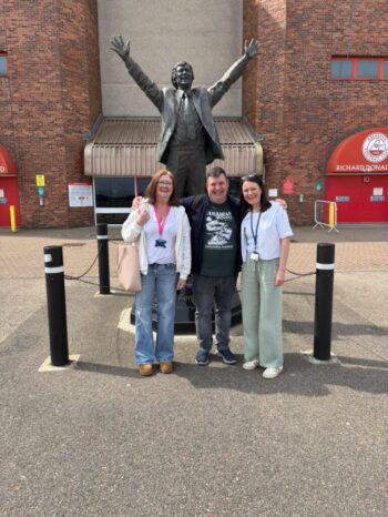 3 NETRALT members in front of Sir Alex Ferguson statue outside Pittodrie Stadium