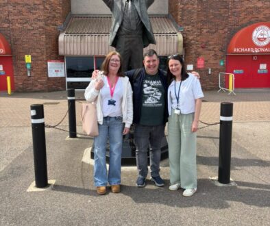3 NETRALT members in front of Sir Alex Ferguson statue outside Pittodrie Stadium